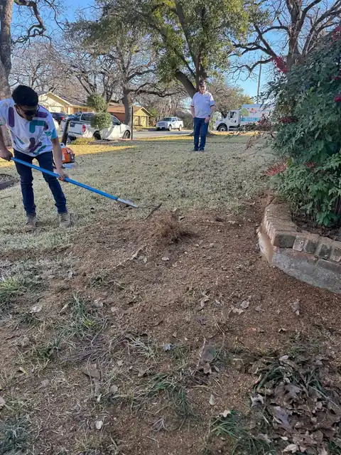 A crew member raking chips level after a stump grind